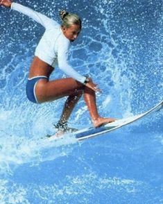 a woman riding a wave on top of a surfboard in the ocean with blue water