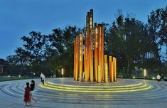 people are standing in front of a large sculpture with lights on it's sides