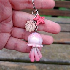 a hand holding a pink and white charm