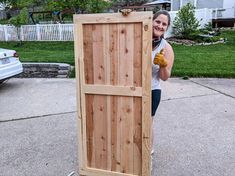 a woman standing in front of a wooden door with gloves on her hands and smiling at the camera