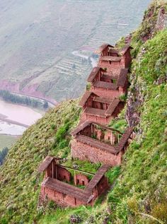 several brick buildings on the side of a hill with grass growing out of it's sides