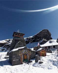 an old stone church in the snow with mountains in the backgrouds behind it