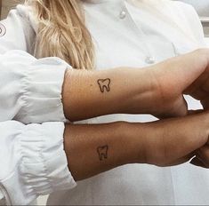 two people with matching tattoos on their arms holding each other's hands in front of the camera