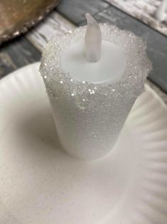 a white candle sitting on top of a paper plate