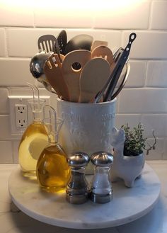 a white pot filled with cooking utensils on top of a marble countertop