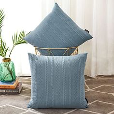 two blue pillows sitting next to each other on top of a rug