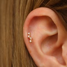 a woman's ear is shown with three small diamond studs on the side