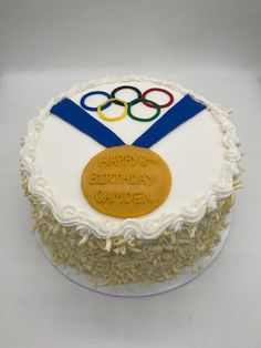 a birthday cake with the olympic symbol on it and some frosting in the shape of a gold medal