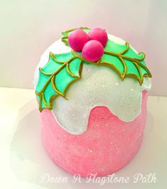 a pink and green frosted cake with holly decorations