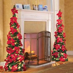 two christmas trees decorated with red poinsettis in front of a fire place