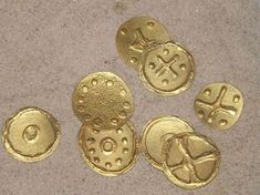 four gold colored buttons sitting on top of a cement floor next to each other with holes in them