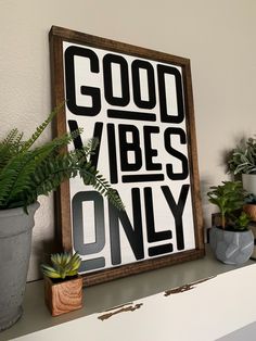 there is a sign that says good vibes only on the shelf next to potted plants