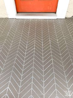 an orange front door with white chevron tiles