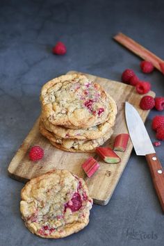 raspberry chocolate chip cookies on a cutting board with a knife and strawberries