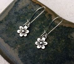 "These are just so sweet and cute! Little daisy dangle earrings. Perfect addition to any outfit and sure to brighten your day! Made from allergy free plated silver. The flowers measure 1/2\" long by 3/8\" wide and hang from 1\" kidney style ear wires that lock and latch. Overall drop length is 1 1/2\". Thanks for stopping by! Please take a moment and visit the rest of my Etsy shop. I have many more unique jewelry designs to choose from! 🌸 Tiger Flower Jewelry 🌸 🌸 Inspired by Nature 🌸" Spring Flower Charm Earrings For Everyday, Everyday Flower Earrings With Spring Charm, Everyday Flower Earrings With Charm For Spring, Everyday Flower Charm Earrings For Spring, Spring Flower Drop Earrings For Everyday, Adjustable Flower Earrings For Everyday, Spring Flower Earrings For Everyday, Adjustable Everyday Flower Earrings, Everyday Flower Earrings For Spring