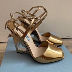 - Prada Heart-Cutout Wedge 110mm Sandal, Platino, Gold - Wedge With Heart Cut Out Elevates Metallic Sandal, - Cutout Metal Wedge Heel, 4.25" (110mm), - Metallic Leather Upper, Peep Toe, Adjustable Ankle Straps, Leather Lining And Sole, - Made In Italy, Gold. Luxury Heels With Wrapped Wedge Heel, Luxury Sandals With Sculpted Wedge Heel, Luxury Wedge Sandals With Wrapped Heel And Round Toe, Luxury Wedge Sandals With Sculpted Heel, Luxury Wedge Heels With Heel Strap, Luxury Platform Wedge Sandals, Luxury Wedge Sandals With Deep Heel Cup, Luxury High Heel Wedge Sandals With Wrapped Heel, Luxury Wedge Sandals With Wrapped High Heel