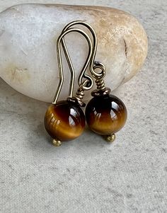 tiger eye earrings   small drop earrings   boho dangle brass earrings * small round Tiger Eye stone beads - 8mm * shades of brown and yellow colors * small metallic brown Czech glass disc sits on top * antiqued brass hook ear wires * total length - 1" * you can enter my shop here:    gypsydangles.etsy.com Brown Brass Dangle Earrings, Brown Brass Drop Earrings, Adjustable Wire Wrapped Brown Earrings, Brown Wire Wrapped Dangle Earrings, Brown Teardrop Brass Earrings, Adjustable Brown Wire Wrapped Earrings, Vintage Brown Round Bead Earrings, Nickel-free Brown Brass Earrings, Bronze Wire Wrapped Round Earrings