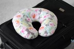 a donut shaped pillow sitting on top of a piece of luggage with floral print