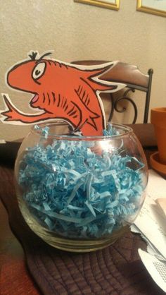 a bowl filled with blue shredded paper on top of a table next to a plate