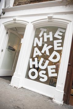 the front window of a shop that has been painted white and says, the naked house