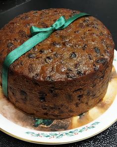 a chocolate cake on a plate with a green ribbon tied around the top and bottom