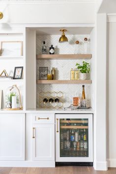 a kitchen with white cabinets and shelves filled with bottles, wine glasses, and other items