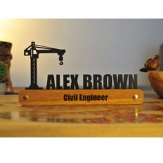 a wooden sign that says alex brown civil engineer on top of a table next to a potted plant