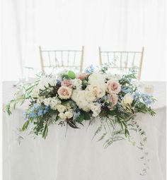 the table is set with flowers and greenery for an elegant centerpiece on it