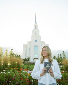 a woman standing in front of a church holding a book