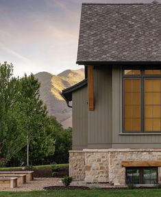 a house with a bench in front of it and mountains in the backround