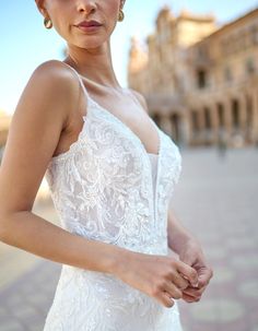 a woman in a wedding dress posing for the camera with her hand on her hip