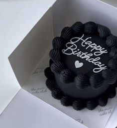 a black birthday cake in a white box with the words happy birthday written on it