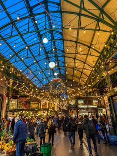 people are walking through an indoor market with christmas lights on the ceiling and decorations hanging from the roof