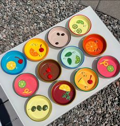 there are many different colored bowls on the table with fruit and vegetables painted on them