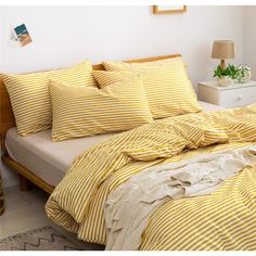 a bed with yellow and white striped comforters on top of it next to a night stand