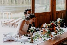 two people sitting at a table with flowers