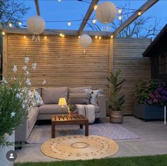 an outdoor living room with lights strung from the ceiling