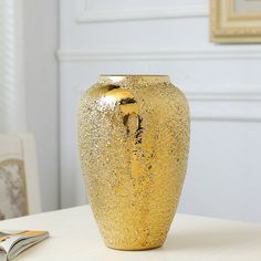 a gold vase sitting on top of a white table