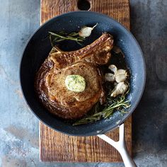 a steak in a skillet with garlic and herbs