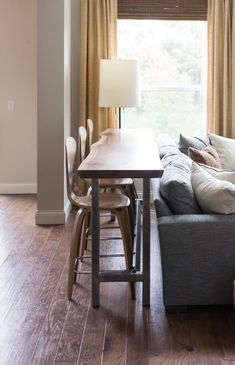 a living room filled with furniture and a wooden table in front of a large window