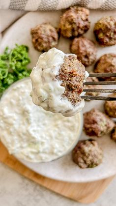 a plate with meatballs and cream sauce on it next to some broccoli