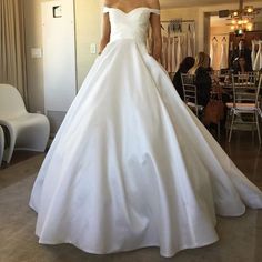 a woman in a white wedding dress standing next to a mirror