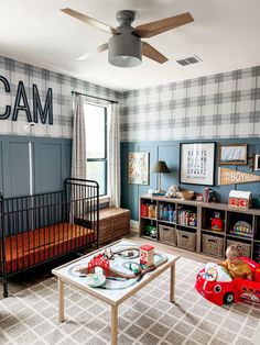 a baby's room with blue walls and plaid wallpaper, a red toy car on the coffee table