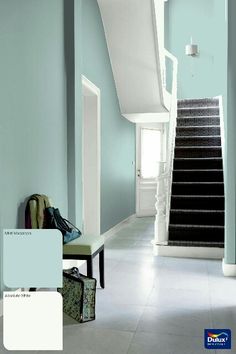 a purple and white hallway with stairs, luggage and handbag on the ground next to it