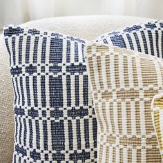 two blue and white pillows sitting on top of a couch