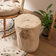 a wooden stool sitting on top of a hard wood floor next to a potted plant