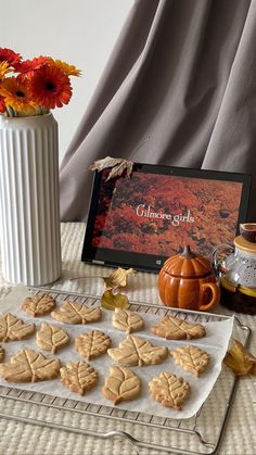 cookies on a cooling rack next to a vase with flowers in it and an autumn card