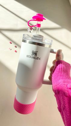 a person in pink sweater holding up a white and pink coffee cup with a pink handle