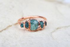 Multi-stone raw emerald ring.  This organic, alternative engagement ring is made out of five uncut, ethically sourced gemstones.  While you'll not receive the same exact ring pictured in photo, you'll receive a very similar one handmade just for you! ✦ Pure copper base with thick (10 micron) plating options in Silver, Rose gold and Gold. ✦ PROCESSING TIME: 1-2 weeks for bare copper and silver plated rings 3-5 weeks for gold and rose gold plated rings ✦ HOW LONG DOES THE PLATING LAST? While most Uncut Gem Engagement Ring, Uncut Emerald Engagement Ring, Raw Stone Engagement Rings Green, Raw Crystal Engagement Rings Bohemian, Crystal Wedding Ring Raw, Emerald Ring Unique, Raw Crystal Engagement Rings By Angeline, Raw Emerald Ring, Crystal Engagement Ring