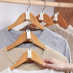 a person is trying to hang clothes on a rack in front of other shirts and sweaters